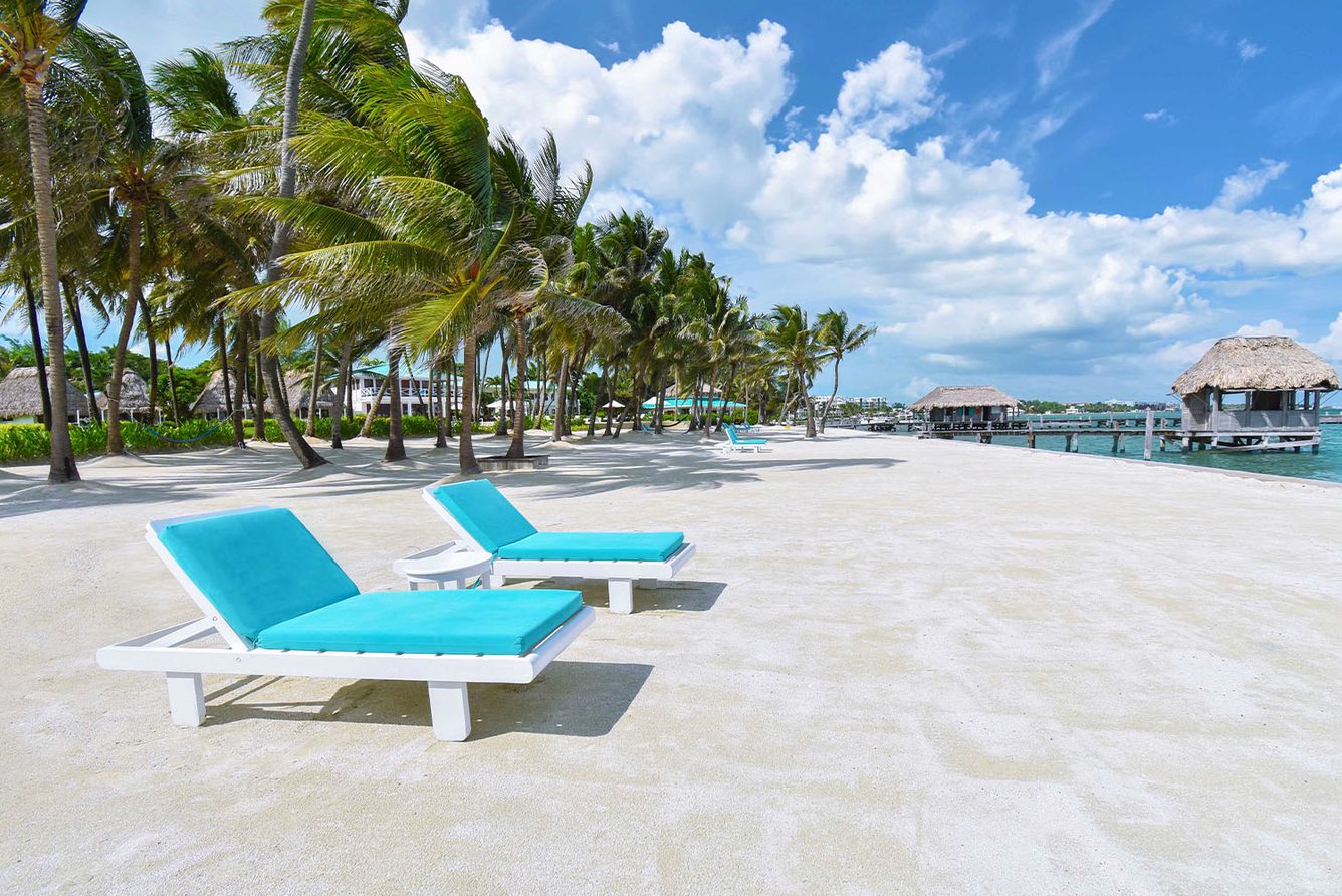 Sun loungers on the white-sand beach at Victoria House, the resort pier in the distance