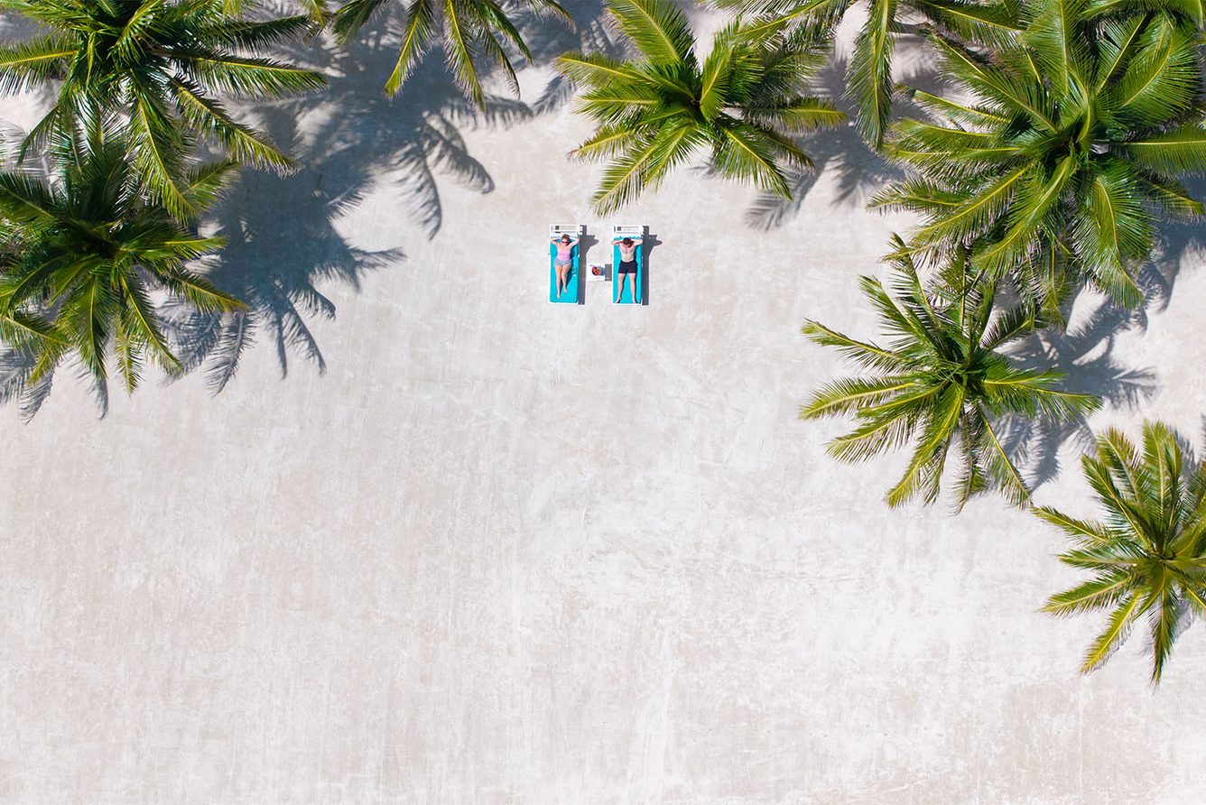Aerial view of palms and white sand along the Victoria House beach