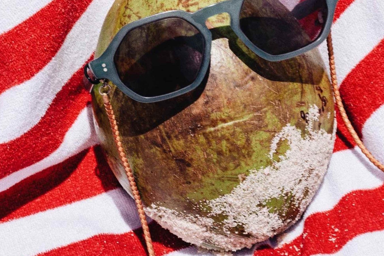A coconut with sunglasses resting on a striped beach towel at Copacabana Palace