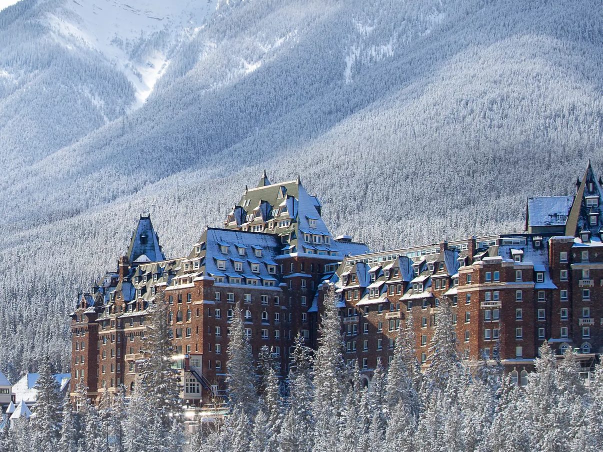 Fairmont Banff Springs in winter, its château-style towers rising above snow-covered forest in Banff National Park