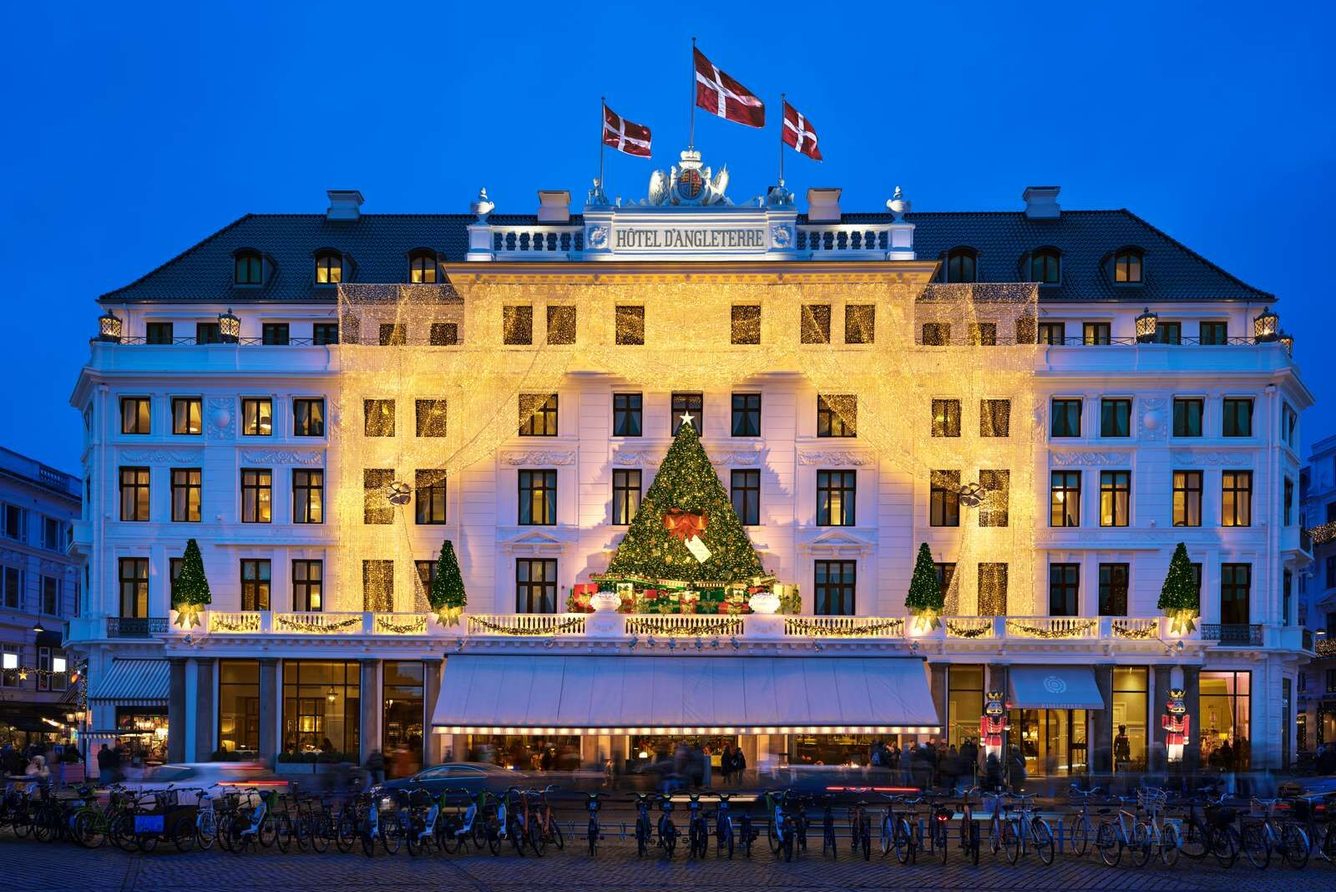 Hotel d'Angleterre's white facade on Kongens Nytorv at dusk, Danish flags flying above the entrance