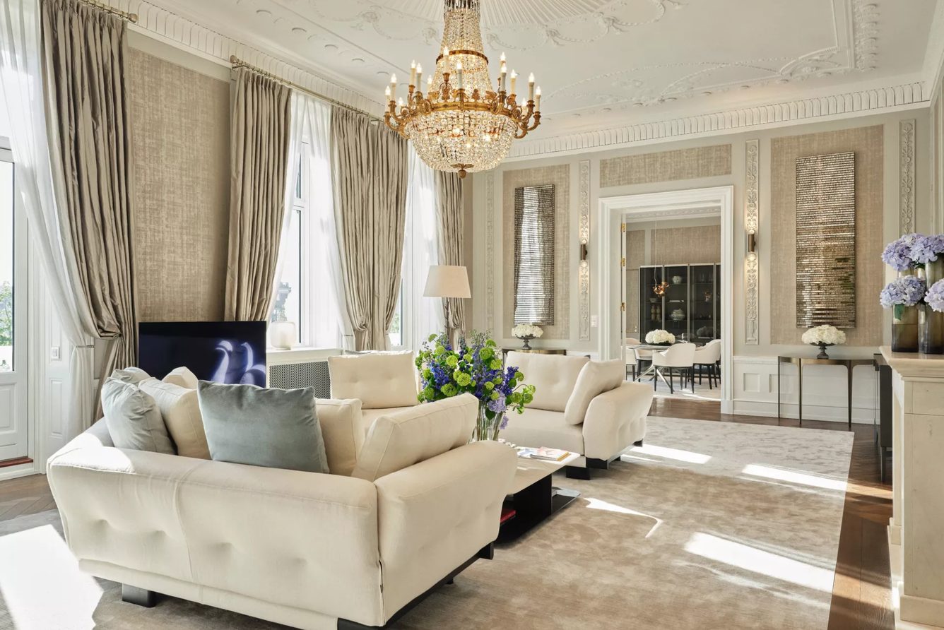 A suite living room at Hotel d'Angleterre, with a chandelier, sofas and tall windows