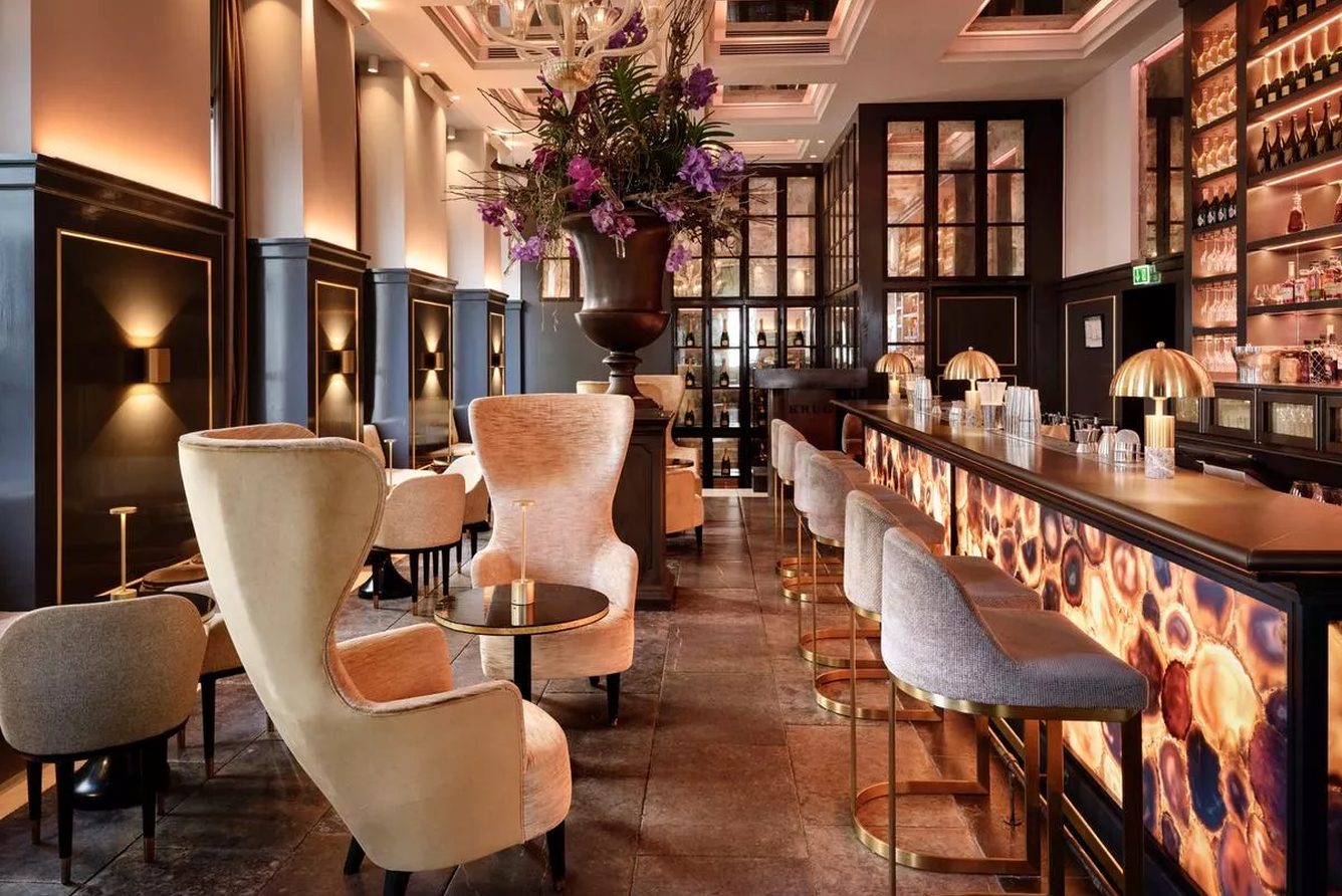 The Balthazar champagne bar at Hotel d'Angleterre, with wing chairs along the bar