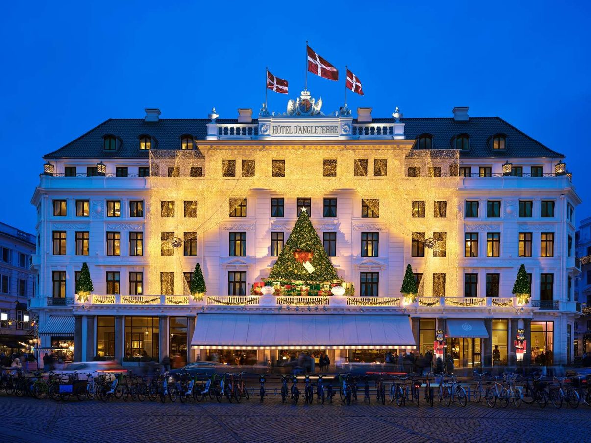 Hotel d'Angleterre's white facade on Kongens Nytorv at dusk, Danish flags flying above the entrance