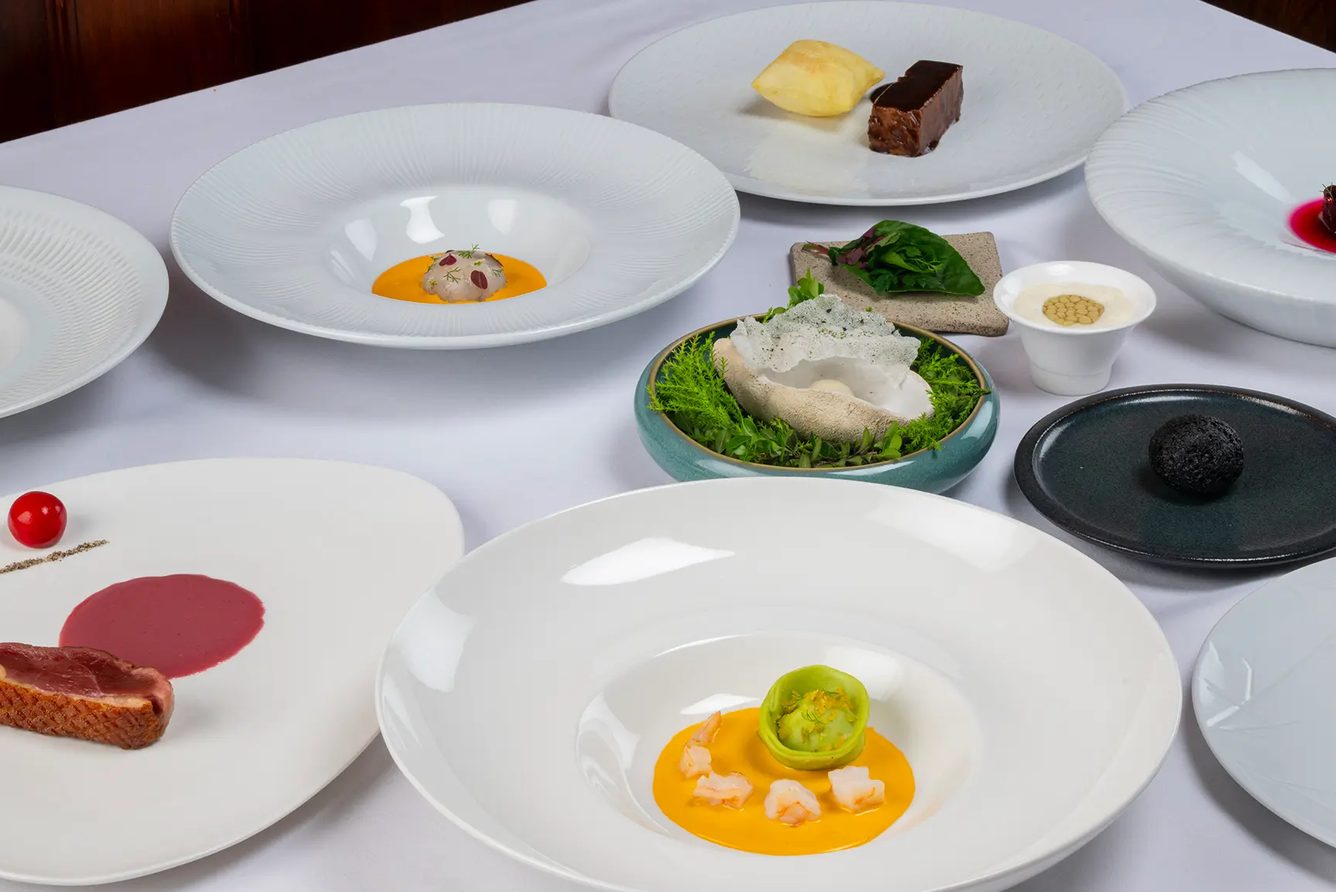 Plated dishes from the ten-course tasting menu on a white tablecloth at Casa Gangotena's restaurant, Quito