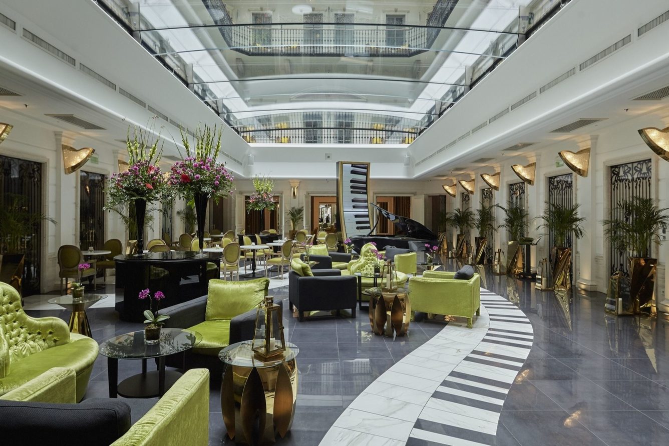 The lobby of Aria Hotel Budapest, its piano-key floor running beneath a glass roof