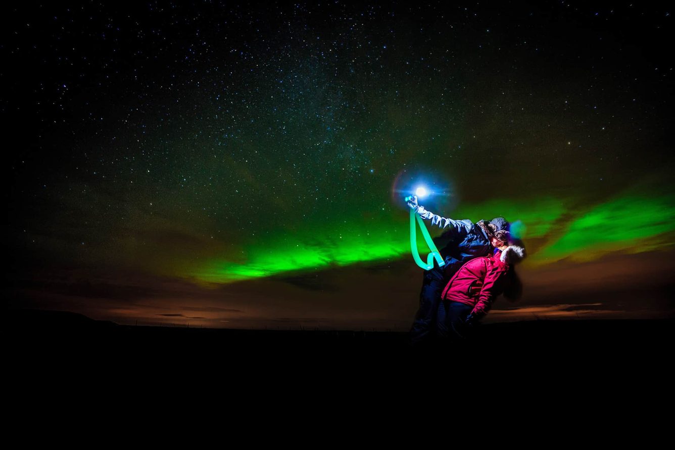 Two guests watching the northern lights in the open country around Hotel Rangá