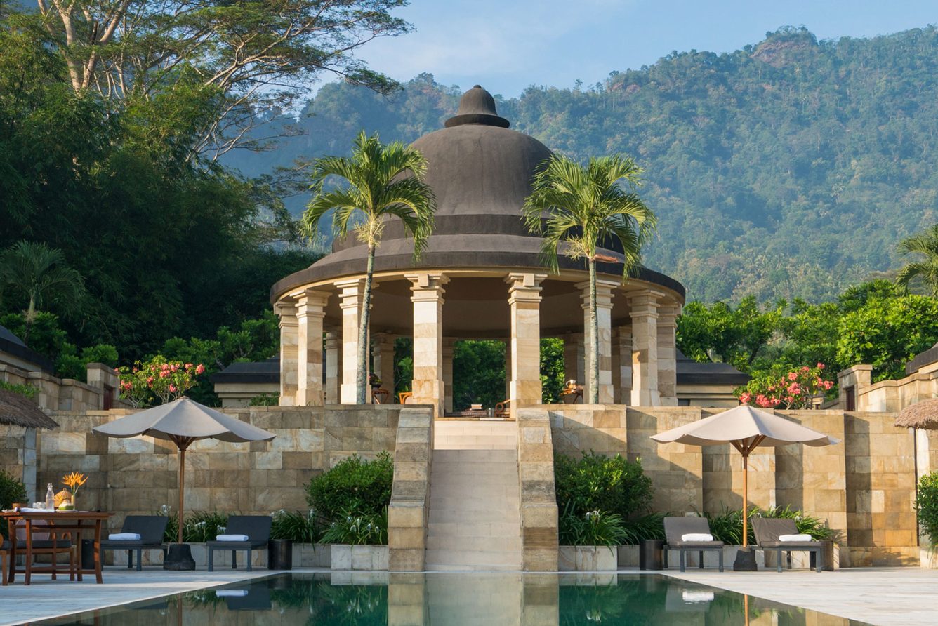 Amanjiwo's domed pavilion and main pool, framed by palms below the Menoreh Hills