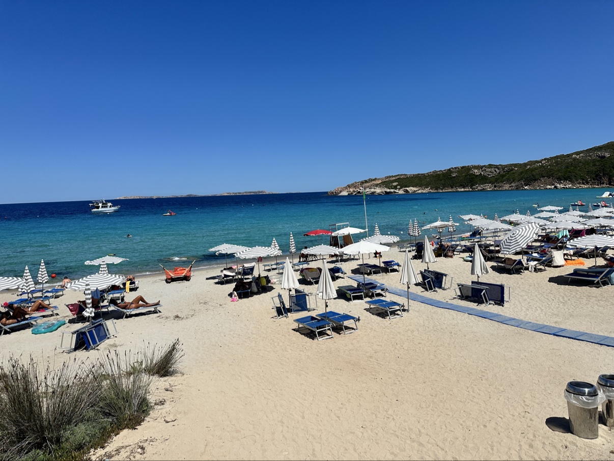 The resort beach at La Marmorata — striped umbrellas, loungers and turquoise water