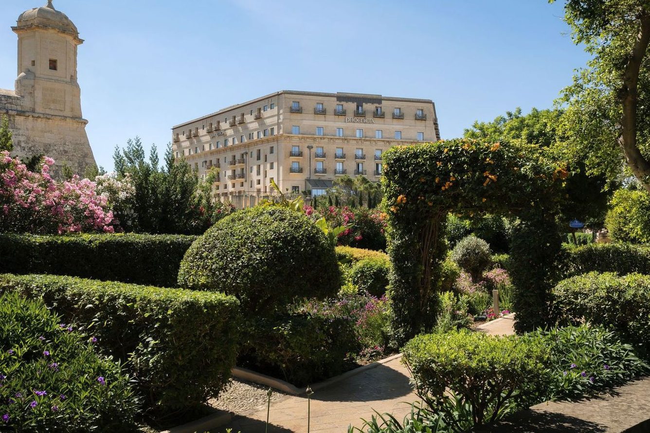 The gardens of The Phoenicia Malta, with the hotel building and a bastion watchtower above Valletta