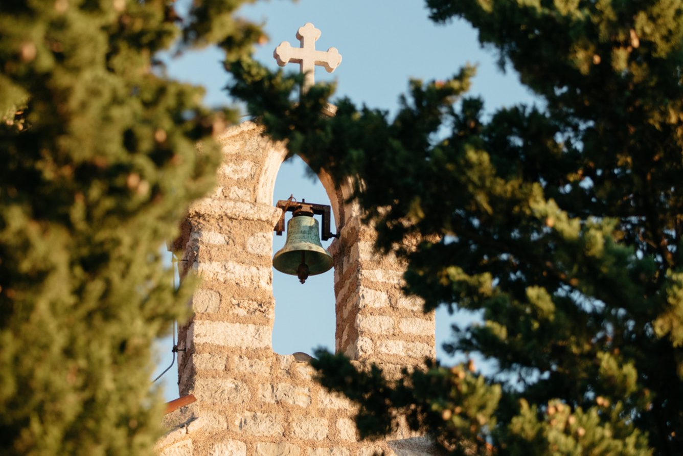 The stone bell tower of the island village church, seen through pine trees