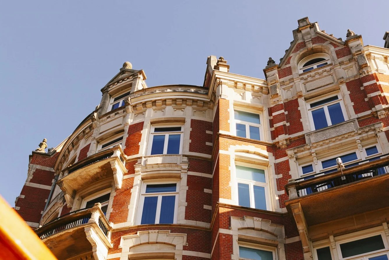 The curved red-brick facade of De L'Europe Amsterdam above the Amstel river