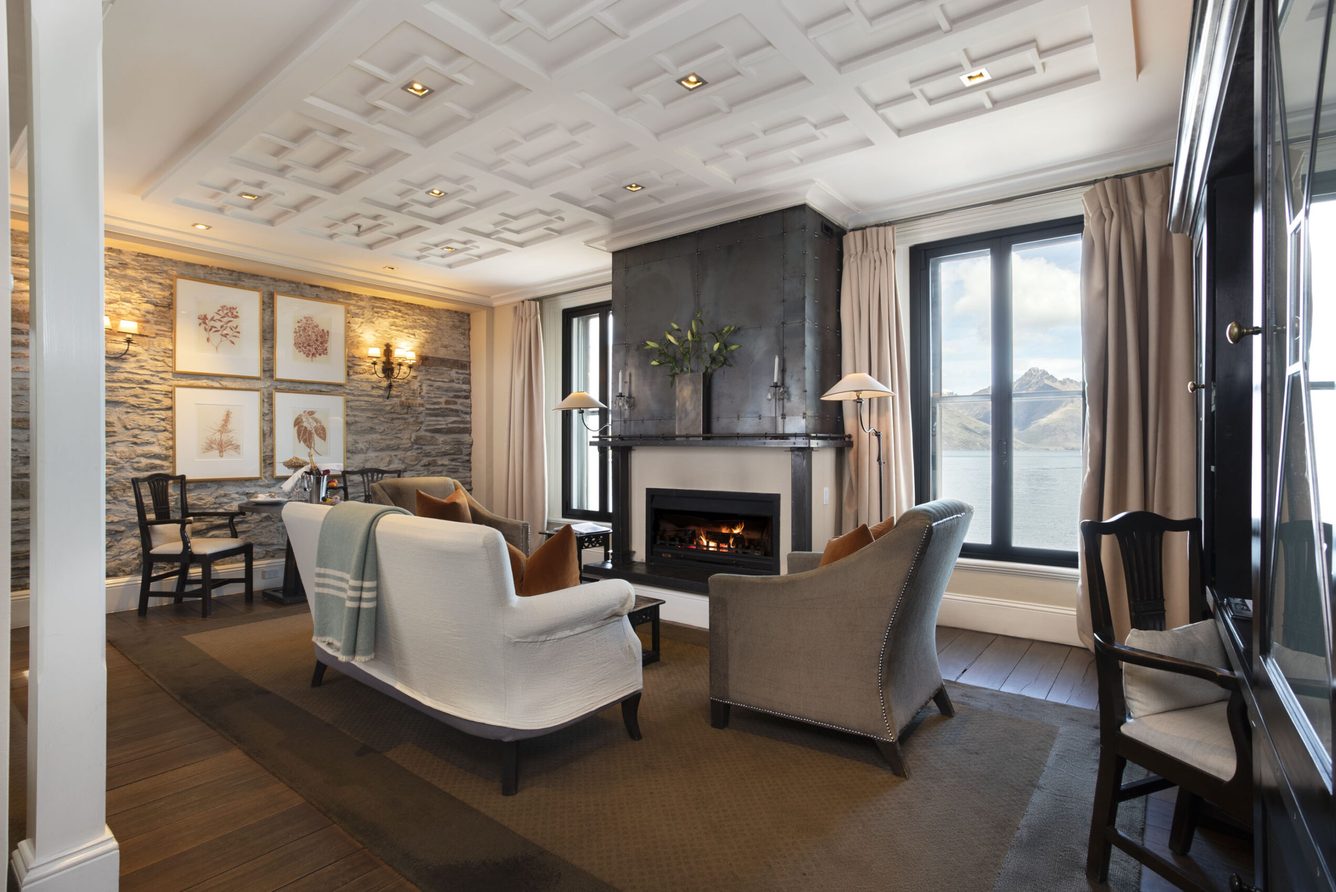 A suite sitting room at Eichardt's Private Hotel with armchairs, a fireplace and lake-view windows