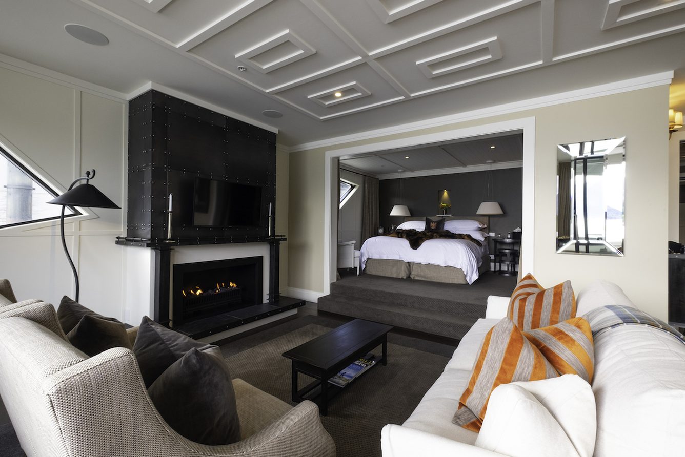 A suite at Eichardt's Private Hotel with a sofa, fireplace and a bedroom beyond