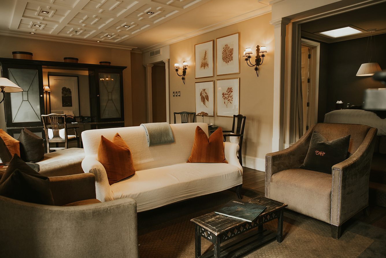 A sitting room at Eichardt's Private Hotel with cream sofas and framed prints on the walls