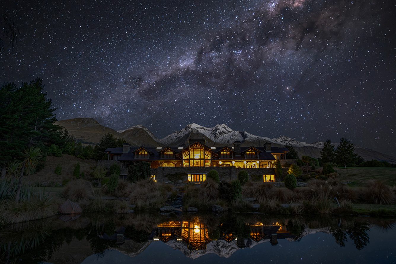 Blanket Bay lodge lit up at night beneath the Milky Way at Glenorchy, at the head of Lake Wakatipu
