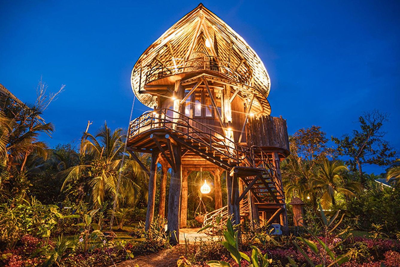 The bamboo treehouse at Nayara Bocas del Toro lit up at dusk in the jungle canopy
