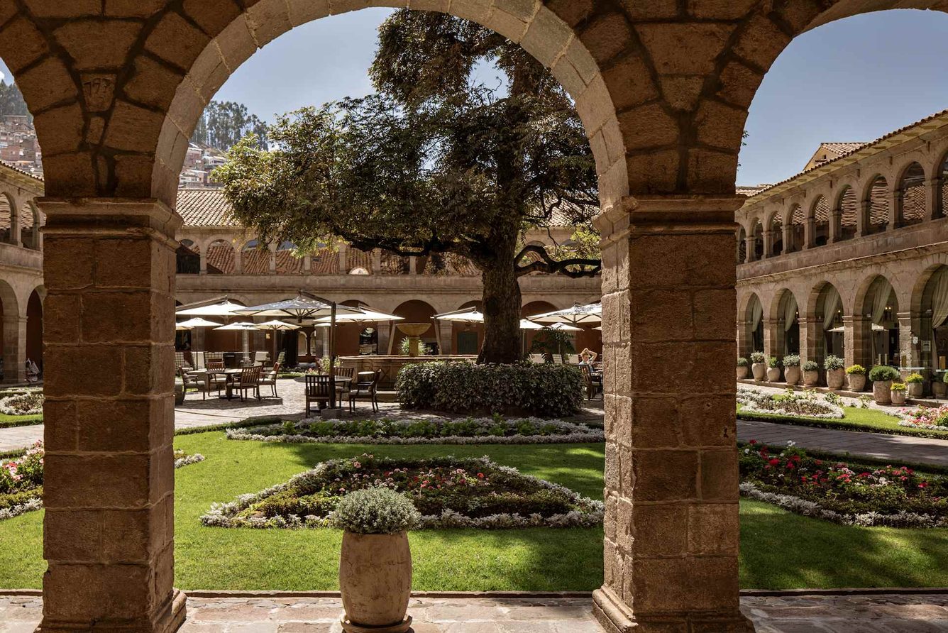 Monasterio's cloistered courtyard in Cusco, seen through stone arches, with its 300-year-old cedar tree