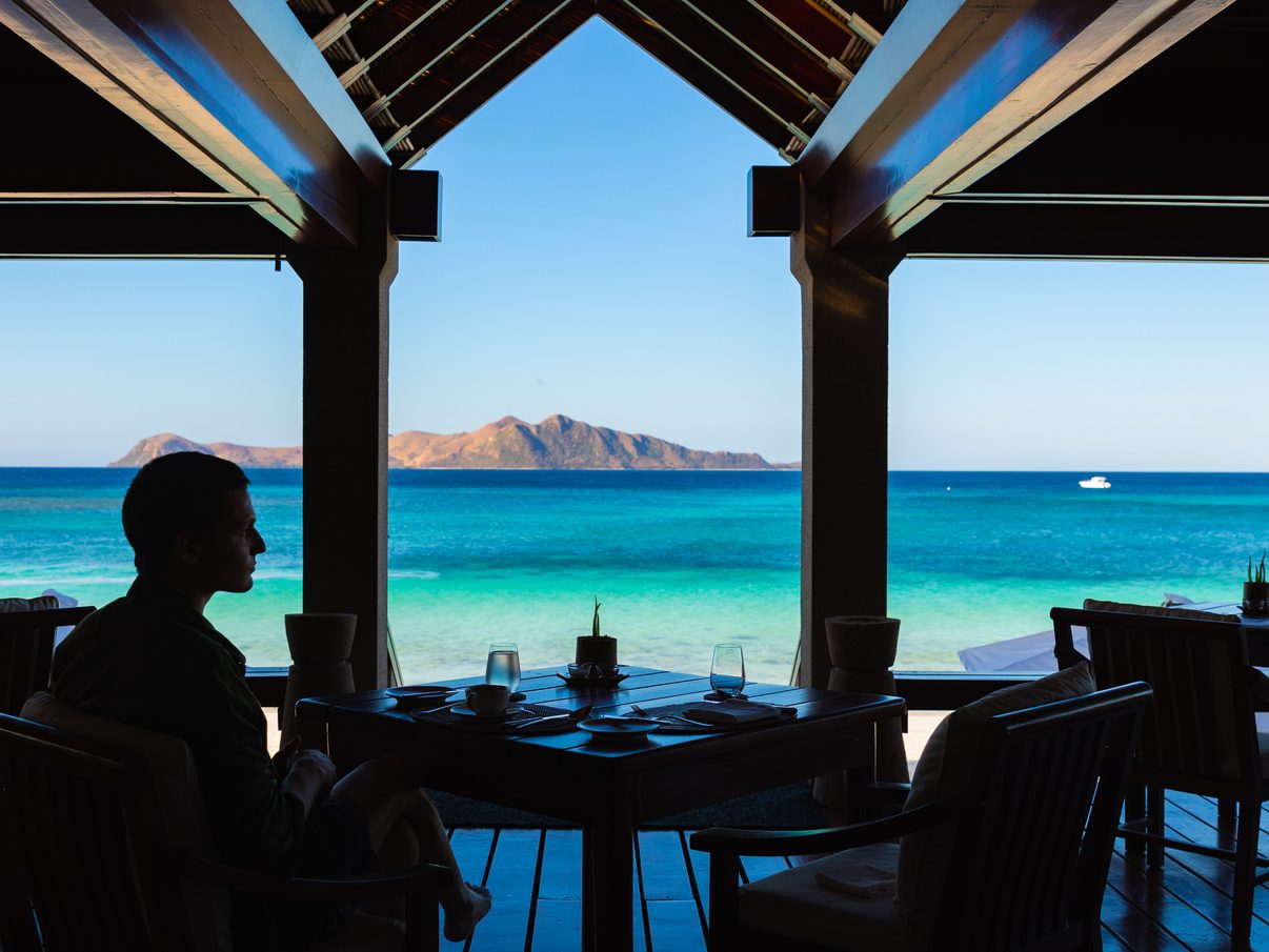 Inside the open-air Beach Club at Amanpulo, a table set for lunch looks across turquoise water to a neighbouring island in the Cuyo Archipelago