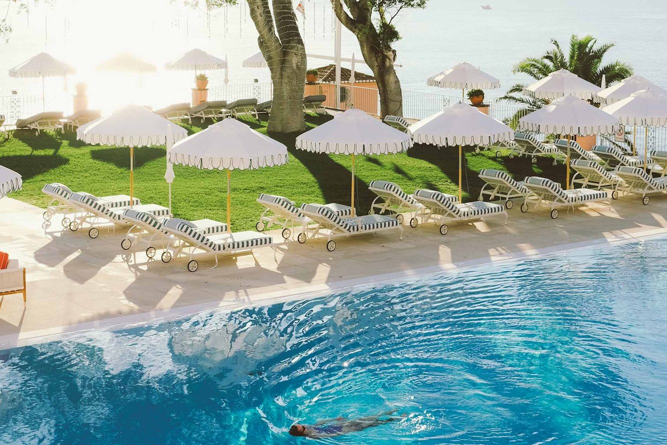 The pool terrace at Reid's Palace, with striped loungers and umbrellas above the Atlantic