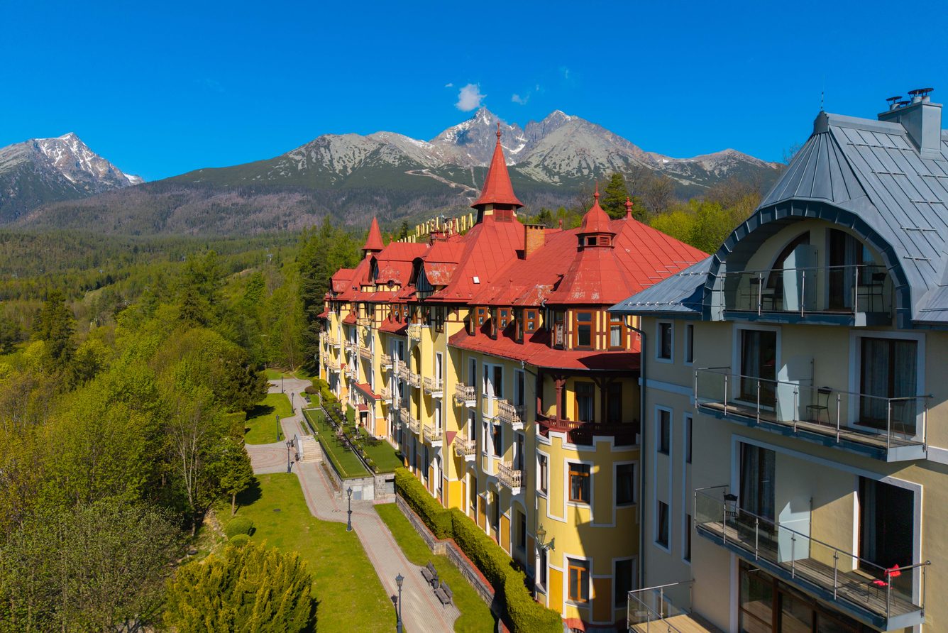 Grandhotel Praha from above, its red roofs set in a green valley below the High Tatra peaks