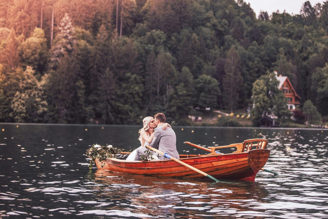 A couple rowing a wooden boat on Lake Bled at golden hour