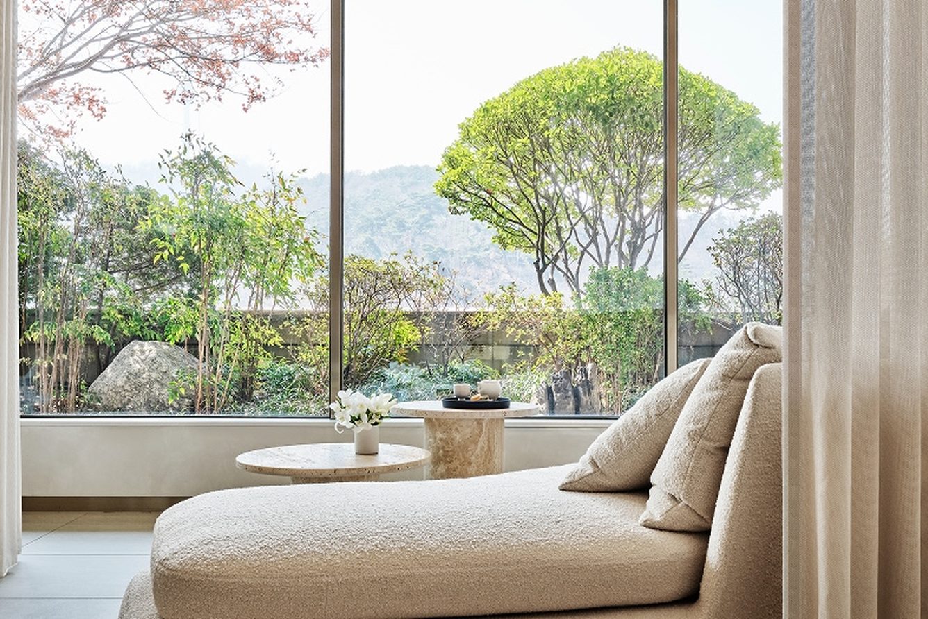 A suite daybed at The Shilla Seoul set before floor-to-ceiling windows over the hotel gardens
