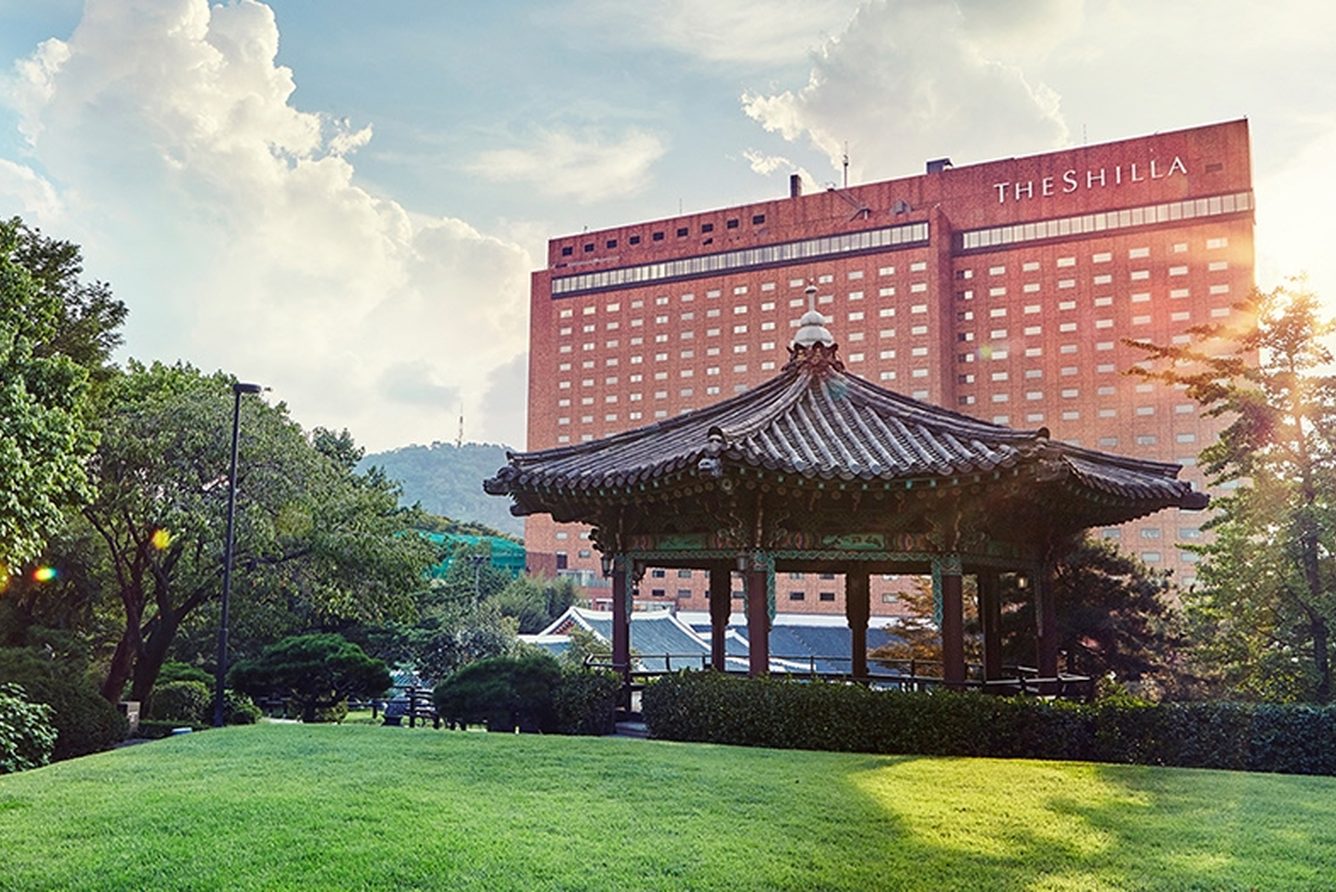 The Shilla Seoul’s red-brick tower rising behind a traditional Korean pavilion and the hotel lawns