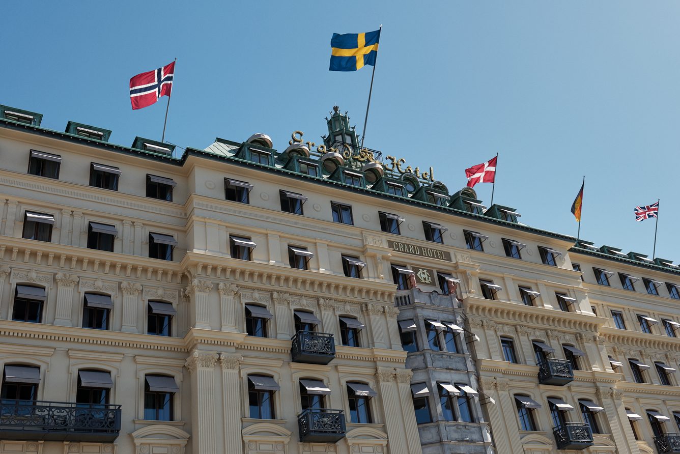 Grand Hotel Stockholm's pale facade on Sodra Blasieholmshamnen, flags flying above the entrance