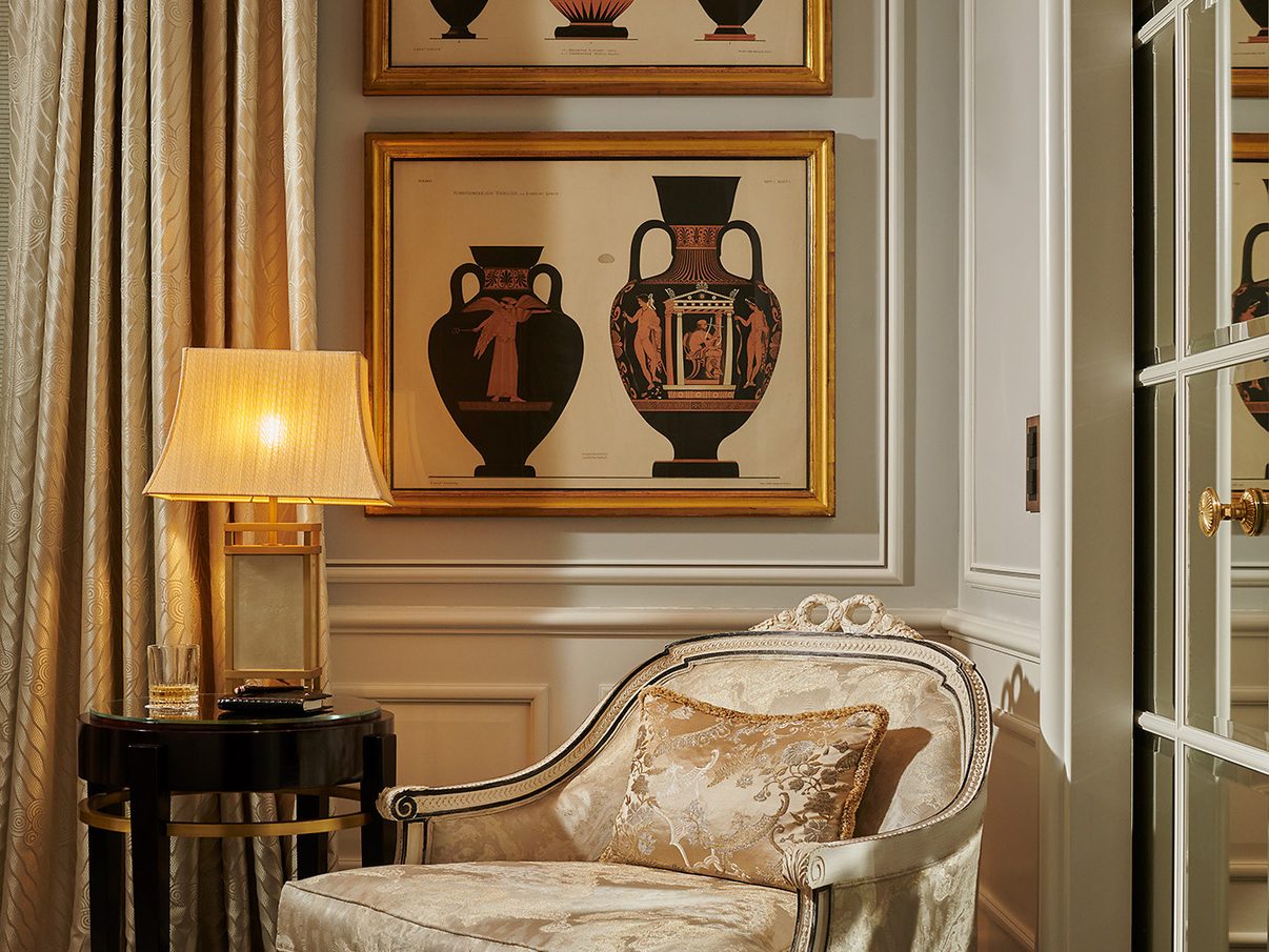 A sitting corner in a suite at Baur au Lac in Zurich, with a chaise longue and framed prints of classical vases