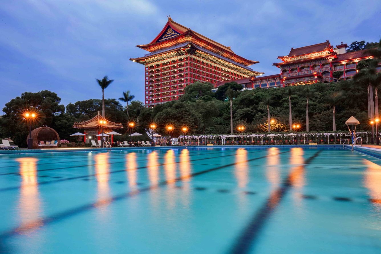 The Grand Hotel Taipei at dusk, seen across its outdoor pool