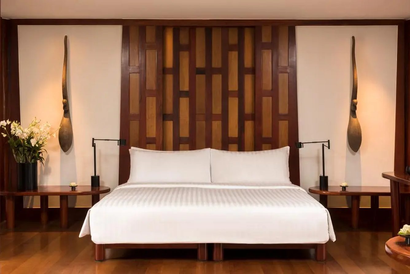 A Pavilion bedroom at Amanpuri with a king bed, teak panelling and muted textiles