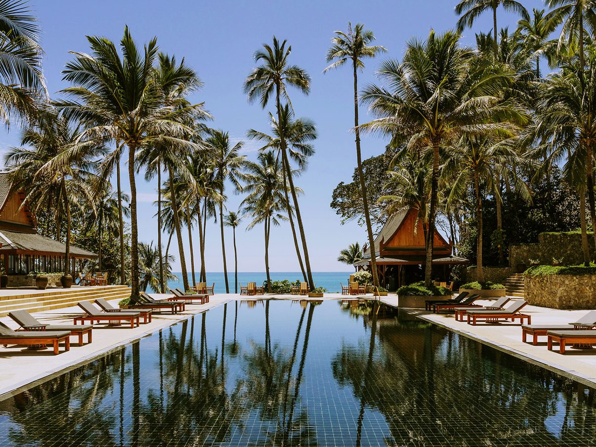 Amanpuri's main swimming pool lined with coconut palms, looking out over Pansea Beach to the Andaman Sea