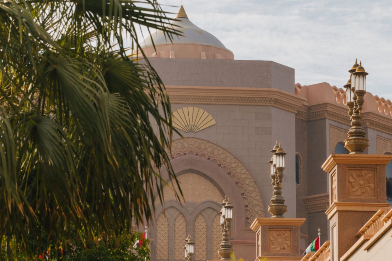 Emirates Palace Mandarin Oriental in Abu Dhabi, its gold domes seen through palm trees