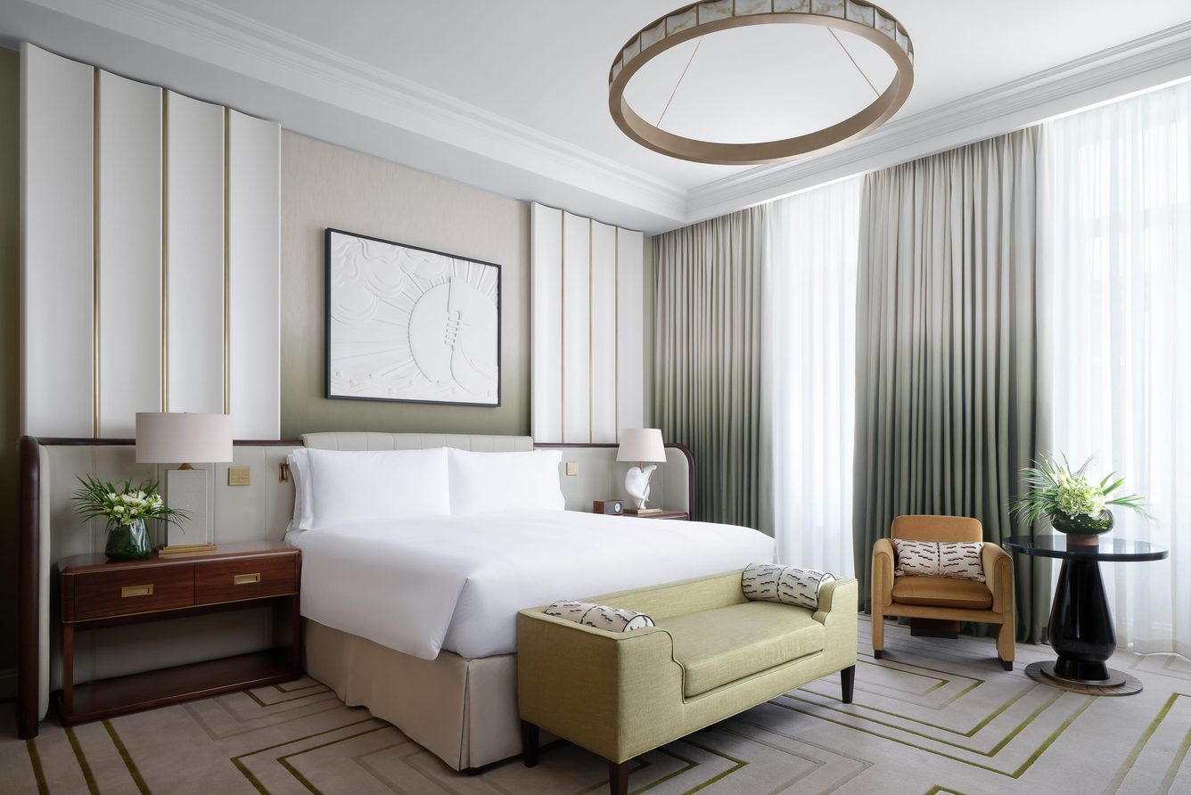 A king bedroom at The Savoy with a pale green bench seat and a circular ceiling light