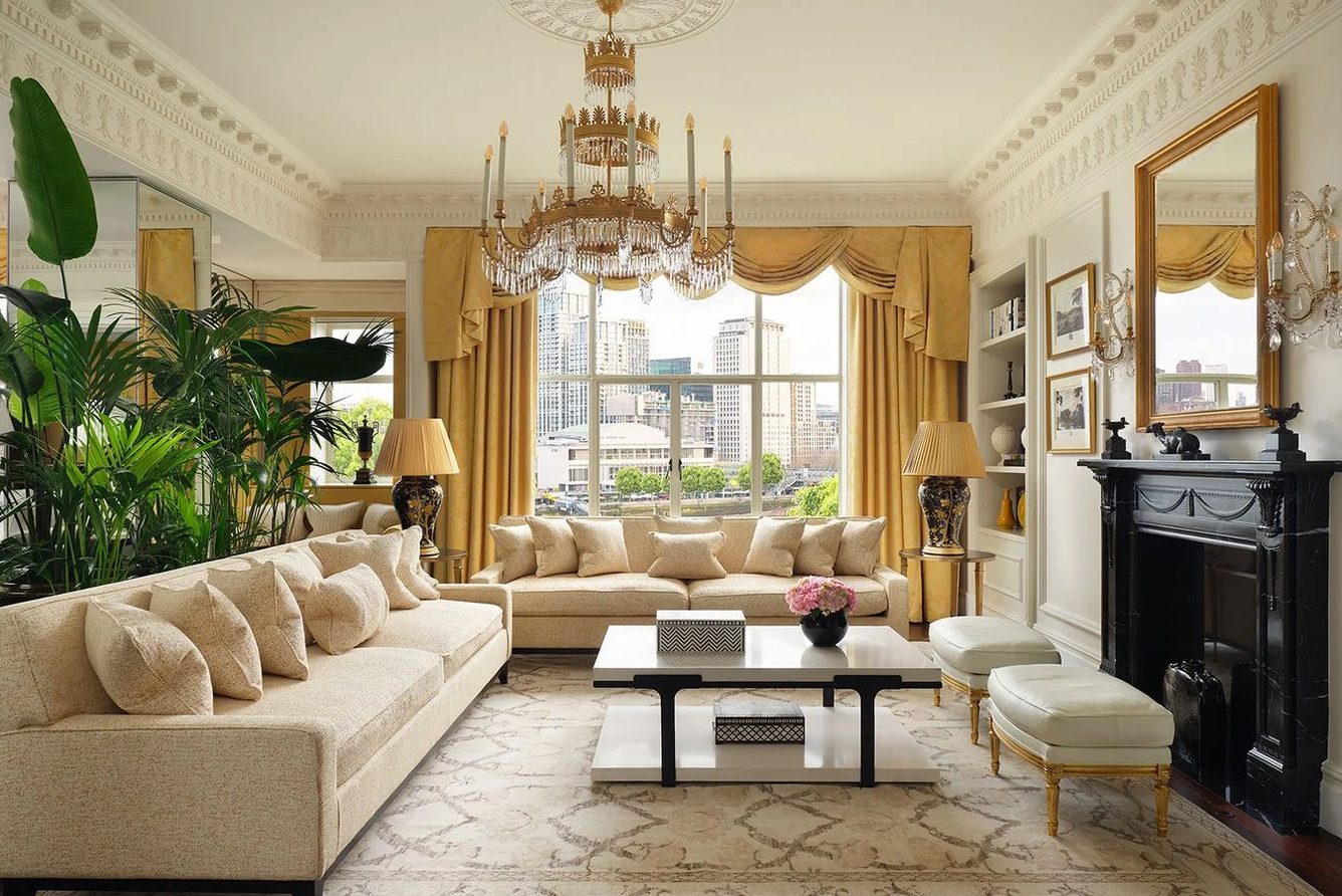 The living room of the Royal Suite at The Savoy, with cream sofas, house plants and a fireplace