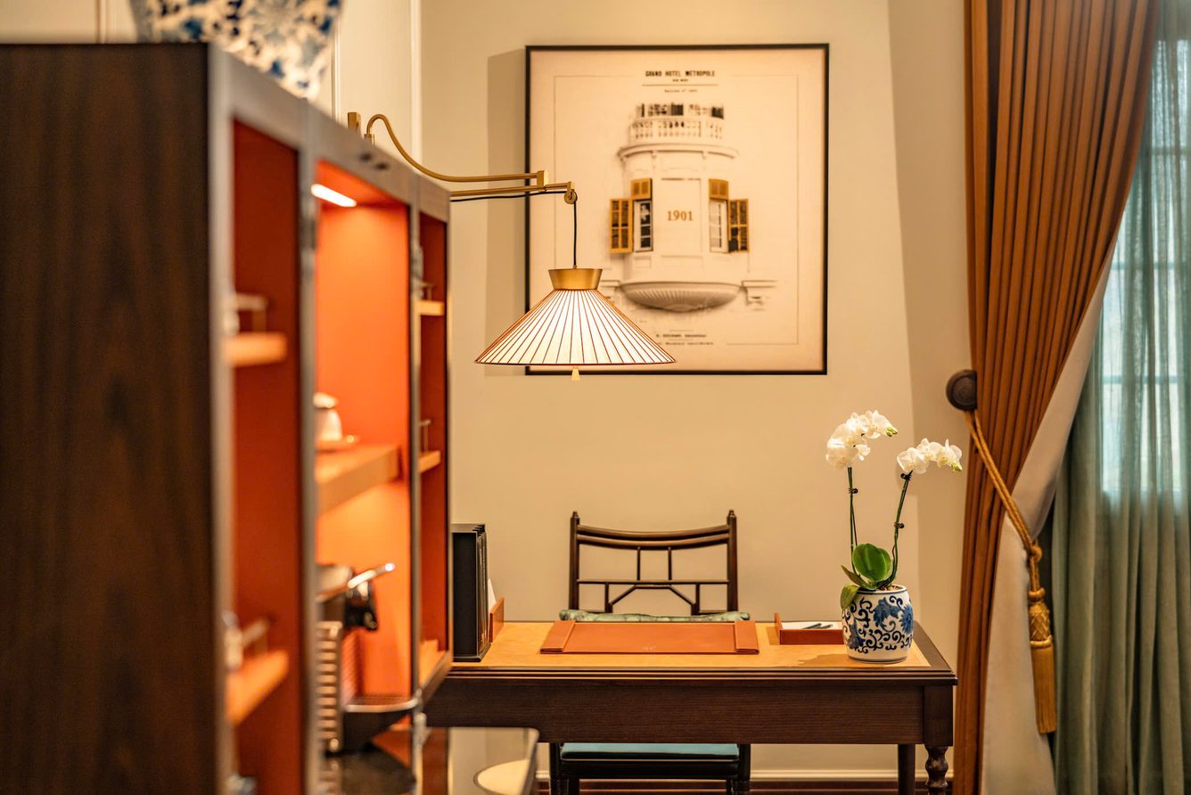 A writing desk with an orchid in a guest room at Sofitel Legend Metropole Hanoi